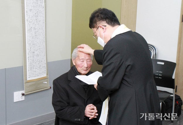 El Padre Joo Young-don impone las manos sobre el anciano Ahn.